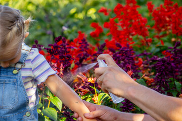 Dad sprays his child with mosquito repellent.