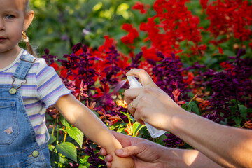 Dad sprays his child with mosquito repellent.