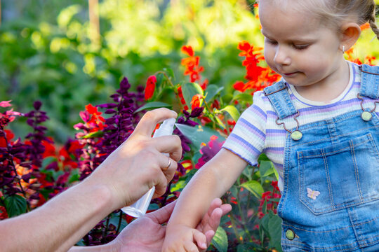 Dad sprays his child with mosquito repellent.