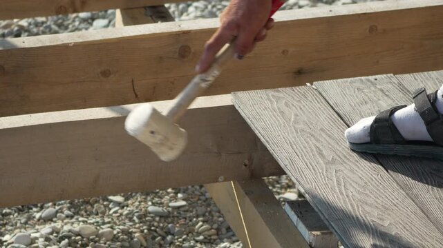 Decking Mallet Installation Hand hammering composite board on wood joists outdoors