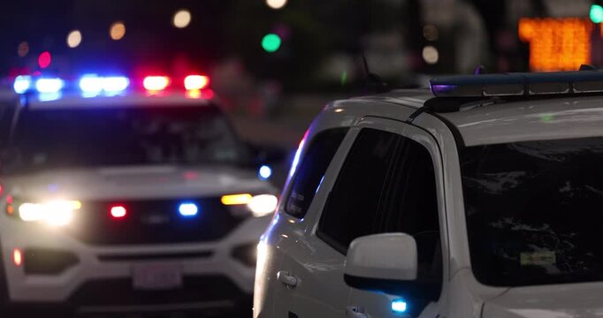 Police units respond to the scene of an emergency with illuminated red and blue lights at dusk.
