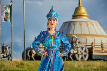 Obraz premium Mongolian girls dressed in luxurious Mongolian costumes in front of a yurt on the grassland