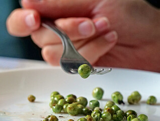 Fork picking up one pea - Macro Detail of a Person Eating Vegetables, Isolating One Single Pea on a...