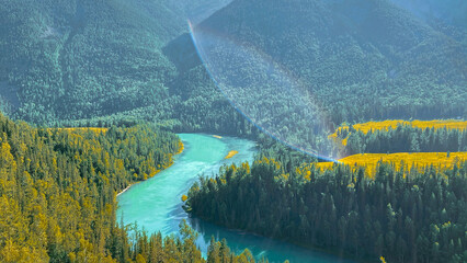 Winding River Through Forested Valley with Rainbow