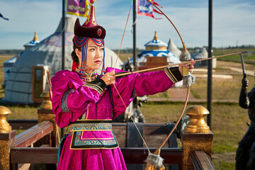 Obraz premium A Mongolian girl dressed in traditional Mongolian attire and holding a bow and arrow in front of a yurt.