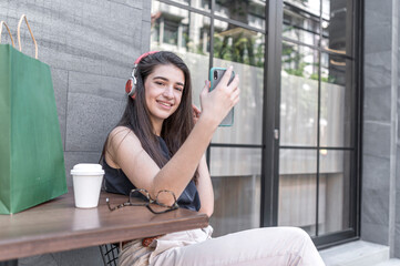 Happy and smiling young shopaholic friends women sit in street coffed cafe and talking after...