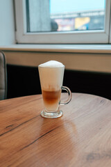 Delicious latte with frothy milk served in a glass at a cozy cafe during the morning hours