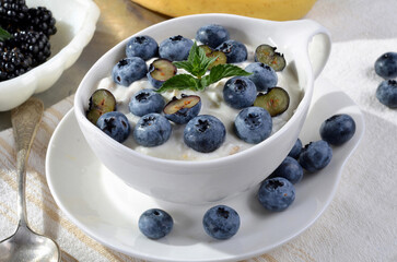 A refreshing blend of creamy yogurt topped with fresh blueberries, banana, mint leaves, served in a...
