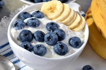 A refreshing blend of creamy yogurt topped with fresh blueberries, banana, mint leaves, served in a bowl.