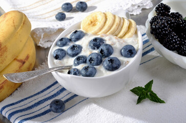 A refreshing blend of creamy yogurt topped with fresh blueberries, banana, mint leaves, served in a...