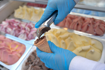 The ice cream man puts ice cream in the cone