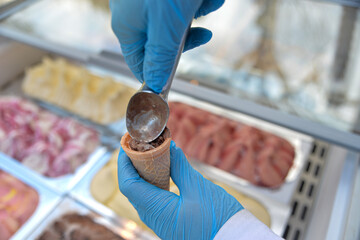 The ice cream man puts ice cream in the cone