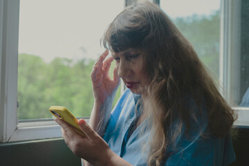 Beautiful old woman chatting on smartphone, placing order online or reading social networks in...