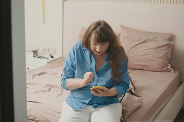 Stylish old woman chatting on smartphone, placing online order or reading social networks in...