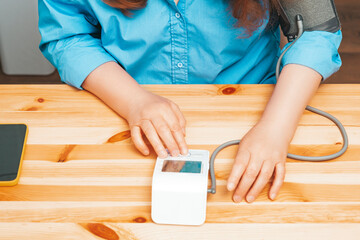 Beautiful elderly woman presses button on tonometer measuring blood pressure in stylish modern...