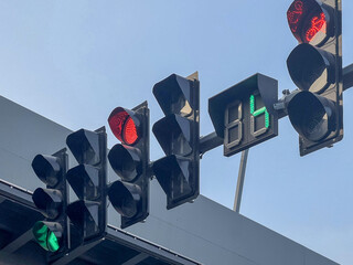 Traffic lights showing red and green signals with a countdown timer against a clear sky