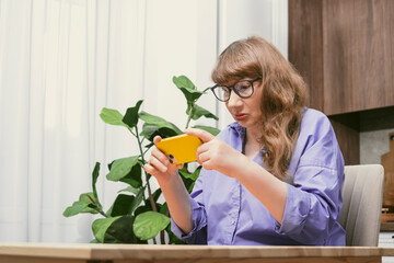 Elderly woman in glasses chatting on smartphone, placing online order or reading social networks...