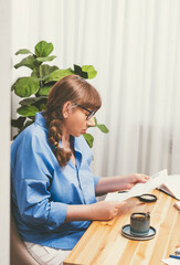 Angry elderly woman involuntarily looking and studying at utility bills in hands while sitting at...