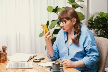 Sociable old woman talking via video link on smartphone in stylish modern flat