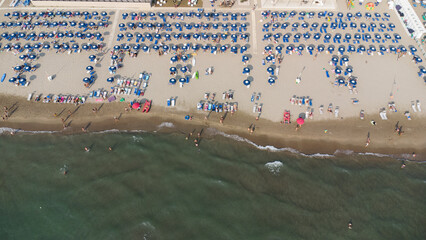 Veduta aerea di spiaggia attrezzata con file di ombrelloni colorati