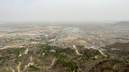 Obraz premium Aerial View of a Hilly Landscape with Urban Development in the Distance