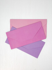 Three pink and lilac closed envelopes for money lie on white background, message concept