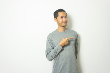 young Adult Asian men wearing grey shirt pointing with finger with smile isolated white background