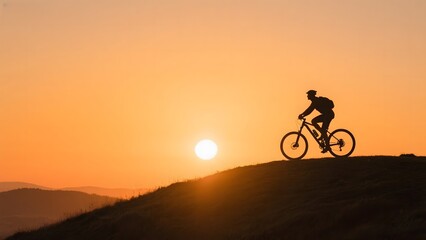 Obraz premium Cyclist Silhouette Riding at Sunset on a Hill