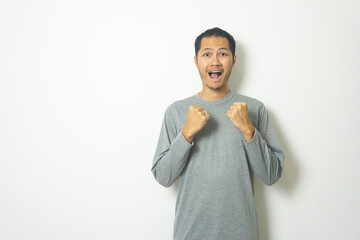 young Adult Asian men wearing grey shirt clenched fist with smile isolated white background