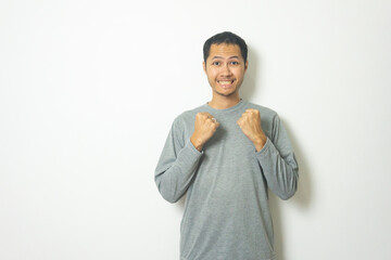 young Adult Asian men wearing grey shirt clenched fist with smile isolated white background