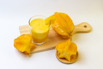 Fresh star fruit smoothie on wooden board showing vibrant color and inviting healthy refreshment.