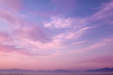 Fototapeta premium A breathtaking vista of a vibrant pink and purple sky at sunrise, with soft clouds and distant mountains creating a serene and dreamy landscape