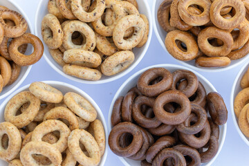 Freshly baked mini bagels on a dark background. Top view. Pretzels in the form of a ring close-up. Small bread circle biscuit. Bowls with different types of bagels.
