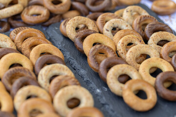 Freshly baked mini bagels on a dark background. Top view. Pretzels in the form of a ring close-up. Small bread circle biscuit. Bowls with different types of bagels.
