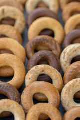 Freshly baked mini bagels on a dark background. Top view. Pretzels in the form of a ring close-up. Small bread circle biscuit. Bowls with different types of bagels.
