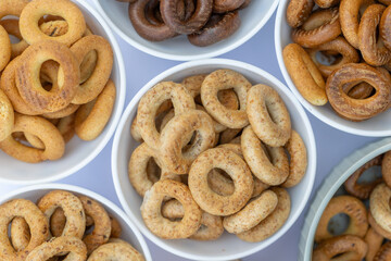 Freshly baked mini bagels on a dark background. Top view. Pretzels in the form of a ring close-up. Small bread circle biscuit. Bowls with different types of bagels.
