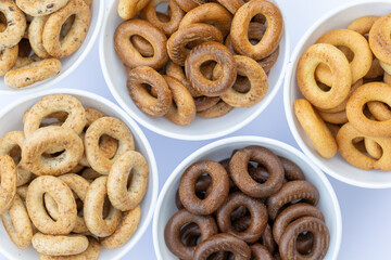 Freshly baked mini bagels on a dark background. Top view. Pretzels in the form of a ring close-up. Small bread circle biscuit. Bowls with different types of bagels.
