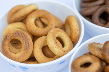 Freshly baked mini bagels on a dark background. Top view. Pretzels in the form of a ring close-up. Small bread circle biscuit. Bowls with different types of bagels.
