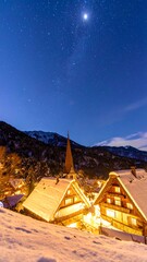 Snow-covered village at night, lit by warm light