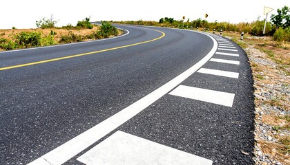 Naklejka premium Winding asphalt road curves gently uphill against a bright, clear sky