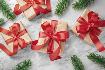 Gift boxes, present with red bow ribbon and christmas tree leaves decor on marble table background
