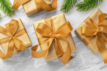 Christmas gift boxes, present with gold bow ribbon and christmas tree leaves decor on marble table...