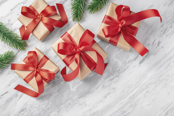 Christmas gift background, present with red bow ribbon and christmas tree leaves decor on marble...