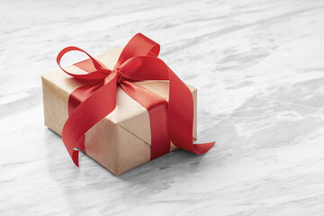 Gift box with red bow ribbon on marble table background, christmas, birthday present