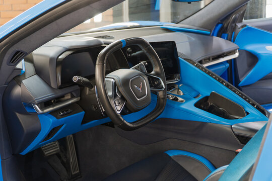 Chevrolet Corvette C8 sport car interior, steering wheel, badge, front seats, central console panel, shift knob, dashboard, armrest. Corvette C8 blue sport car from USA. GM. 