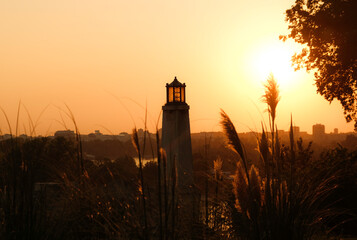 Silhouette of a stone lantern tower at sunset in Belgrade, with golden sunlight illuminating tall...