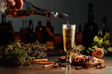 Yellow herbal liquor or mixture is poured from a vintage bottle into a glass.