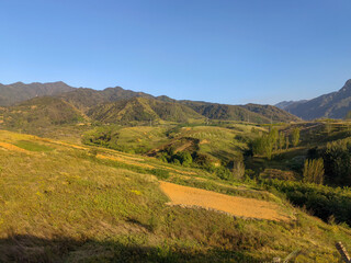 Rolling Hills and Mountain Range Under Clear Blue Sky