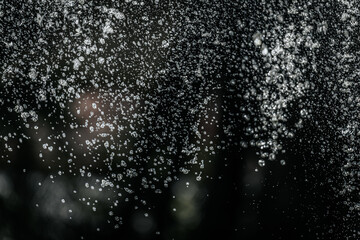 suspended water droplets in motion against a dark background, creating a sparkling abstract pattern with light reflections.