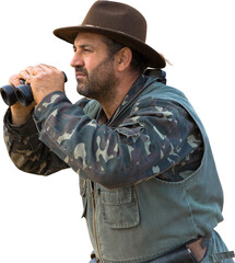 A hunter in a hat with binoculars looks out for prey